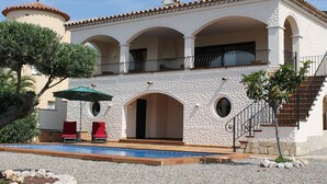 A two-story building with a pool, outdoor seating, and a staircase.