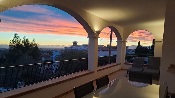 A balcony with a view of a sunset over a cityscape.