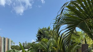 A pool area with a wooden deck, lounge chairs, and a metal pool ladder. - Villa ATOLA with swimming pool 800m from Le Diamant beach in Martinique. (Le Diamant)