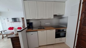 Una cucina compatta con pensili e basi bianche, lavastoviglie, piano cottura e lavello.