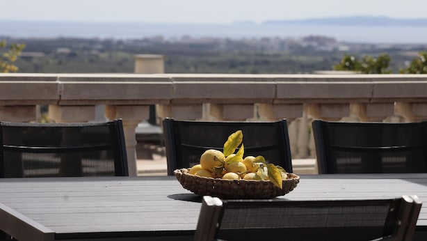 Una mesa con una cesta de limones en una terraza con vistas a la ciudad.