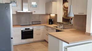 Una cocina moderna con armarios blancos, horno empotrado, cafetera y una ventana sobre el fregadero.