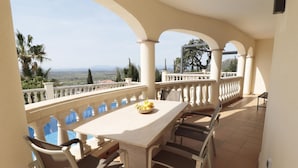 Una terraza con mesa y sillas, vistas del paisaje y una piscina.