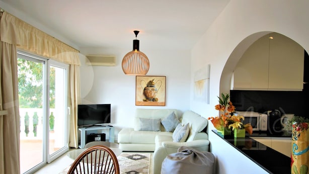 Una sala de estar moderna con un sofá, una televisión y un comedor con una mesa y sillas.