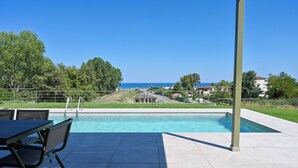 Ein Schwimmbecken mit Blick auf das Meer und Häuser im Hintergrund.