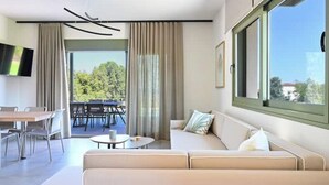 Ein modernes Wohnzimmer mit einer Couch, einem Esstisch und einem an der Wand befestigten Fernseher.
