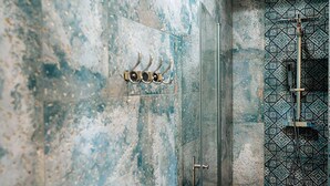 Une salle de bain avec un mur en marbre, une douche en verre et un mur recouvert de carreaux décoratifs.