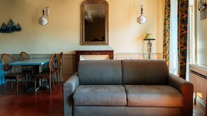 Un salon comprenant un canapé, une table à manger avec des chaises, un miroir et une lampe.