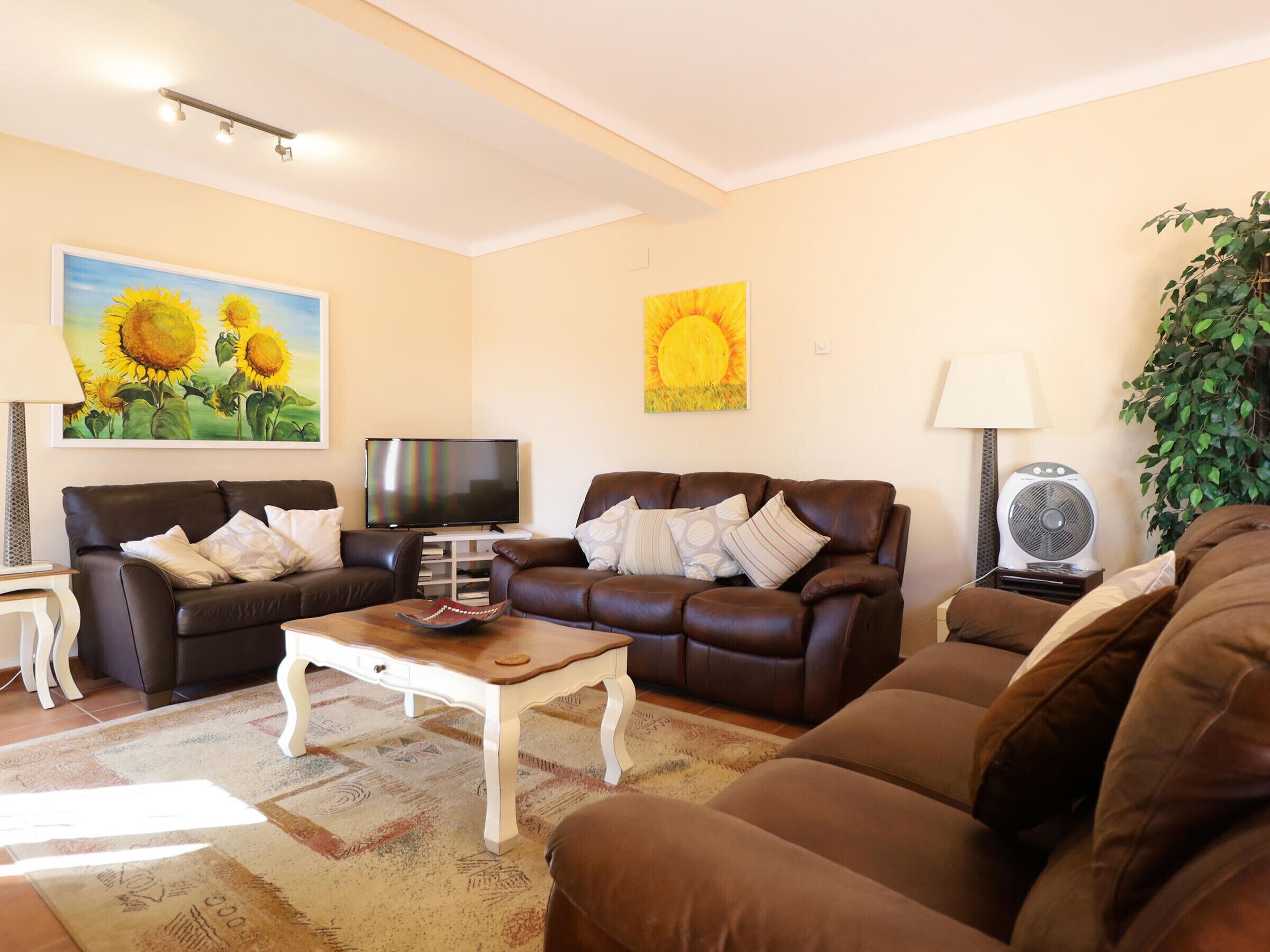 Ein Wohnzimmer mit zwei braunen Ledersofas, einem Couchtisch, einem Fernseher und Kunstwerken an den Wänden.