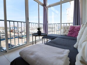 A balcony with a view of a marina, a small table with a plant, and a sofa with cushions. - Air-Conditioned Apartment with Elevator in Santa Margarita (Roses)