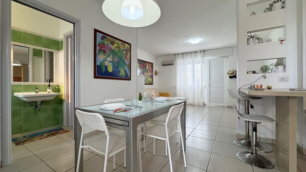 Una cocina moderna con comedor, mobiliario blanco y obras de arte coloridas en las paredes.