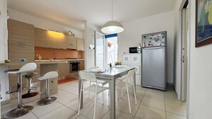 Una cocina moderna con comedor, que incluye una isla central, taburetes de bar y un refrigerador con imanes.