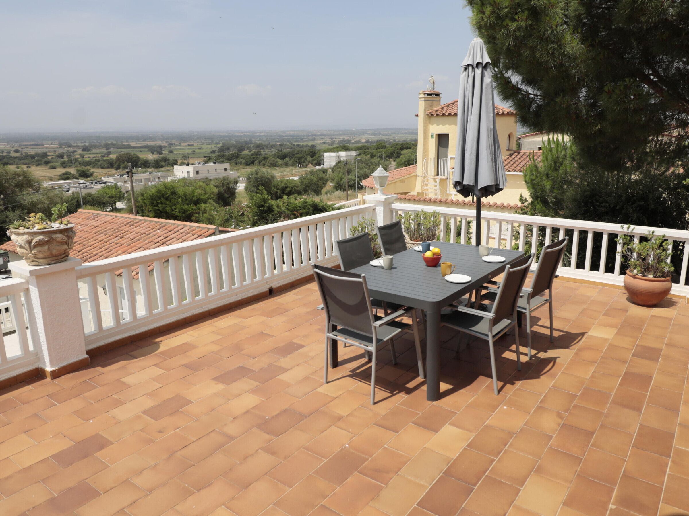 A terrace with a table and chairs, a potted plant, and a view of the countryside.