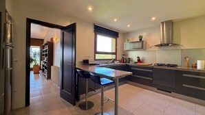A modern kitchen with a central island, dark cabinetry, and a window providing natural light. - Spacious house with air conditioning and pets allowed in Pau (Pau)