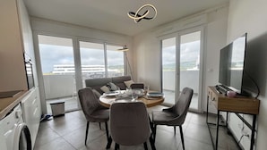 A modern apartment with a dining area, a sofa, a TV, and a washing machine. - Beautiful new apartment for 4 with terrace, Cap d'Agde (Cap d'Agde)