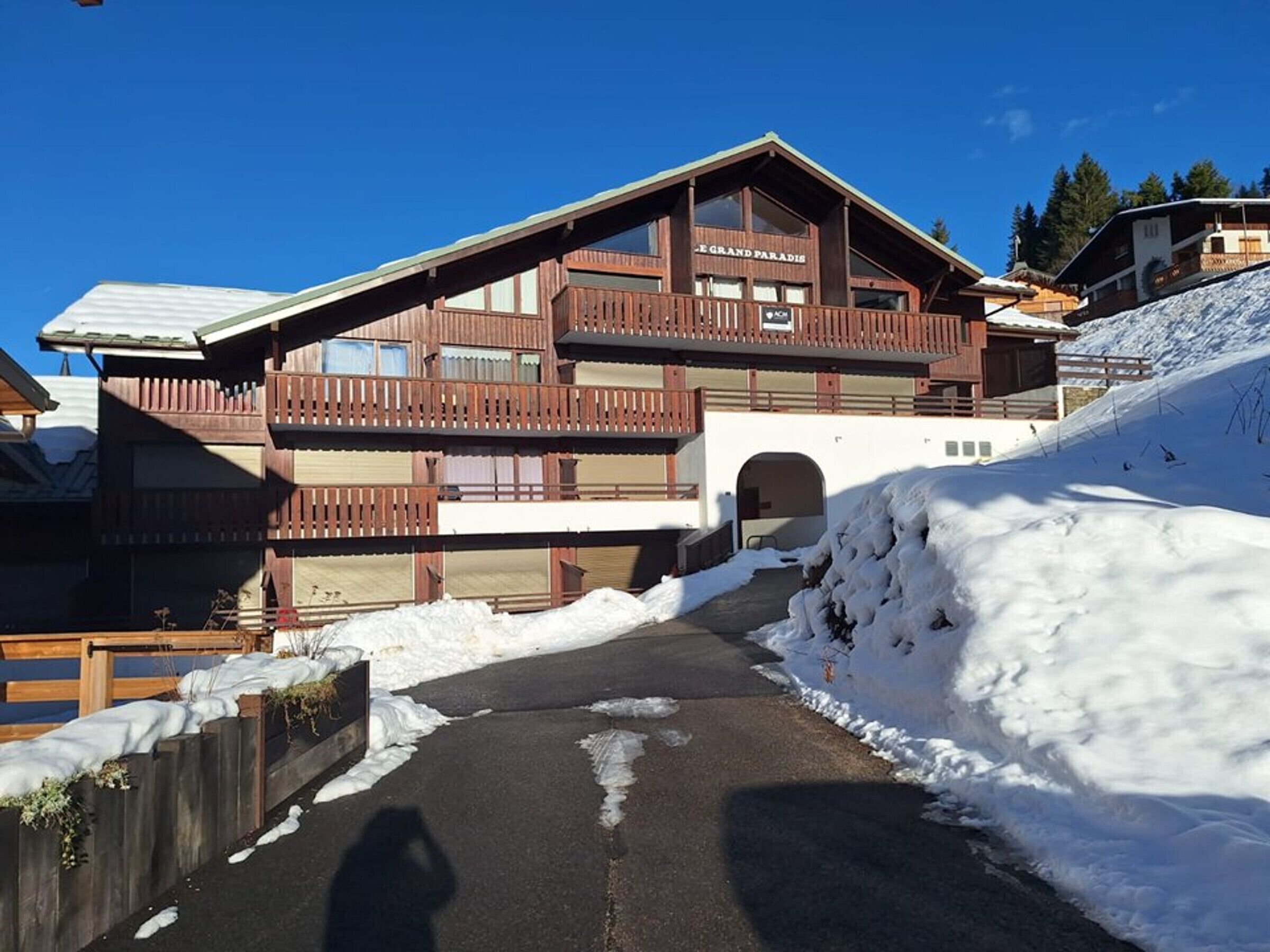 A two-story wooden building with balconies and a ski slope in the background.