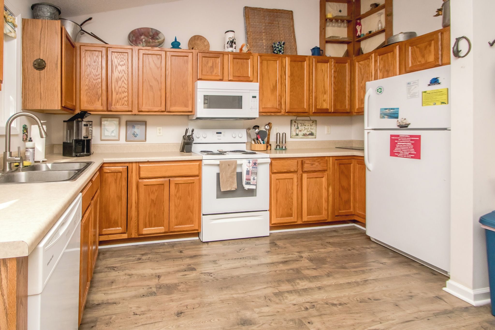 A kitchen with wooden cabinets, a white stove, a microwave, and a refrigerator.