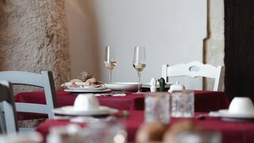 Una mesa de comedor con platos, vasos y cubiertos, con mantel rojo y una silla blanca.