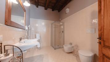 A bathroom with a large mirror, a sink, a shower enclosure, a bidet, and a toilet.