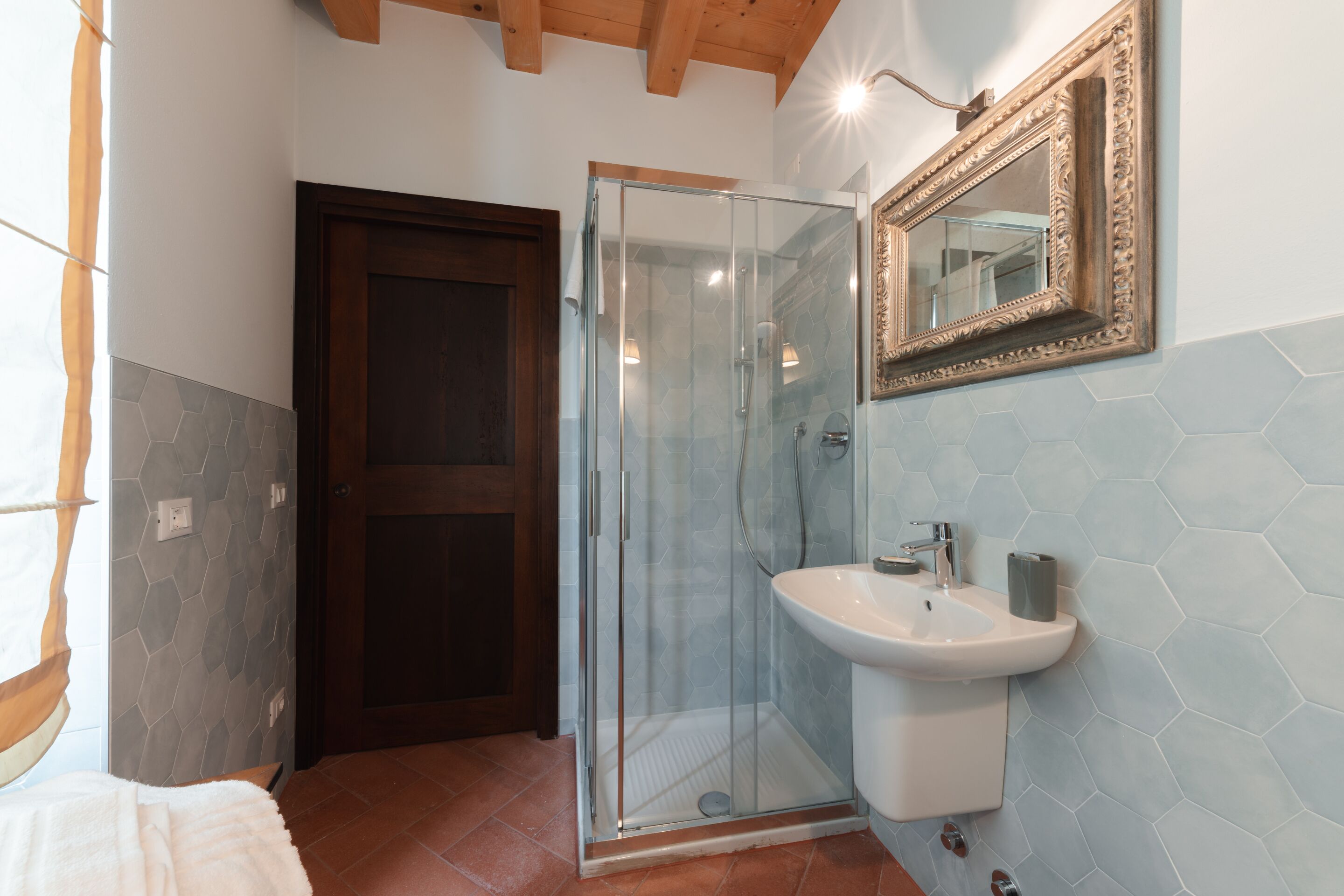 Une salle de bain avec une douche à parois de verre, un lavabo et un miroir au mur.
