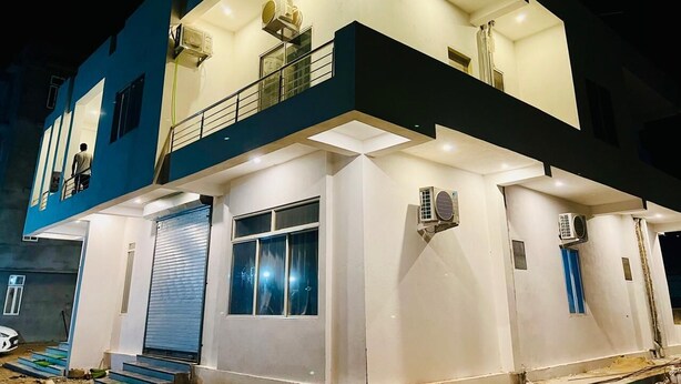 Un immeuble de deux étages doté d’un balcon, de grandes fenêtres et d’un appareil de climatisation fixé au mur extérieur.