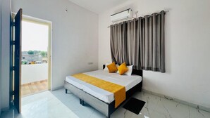 Une chambre à coucher avec un lit, un ventilateur de plafond, un appareil de climatisation et une fenêtre avec des rideaux.