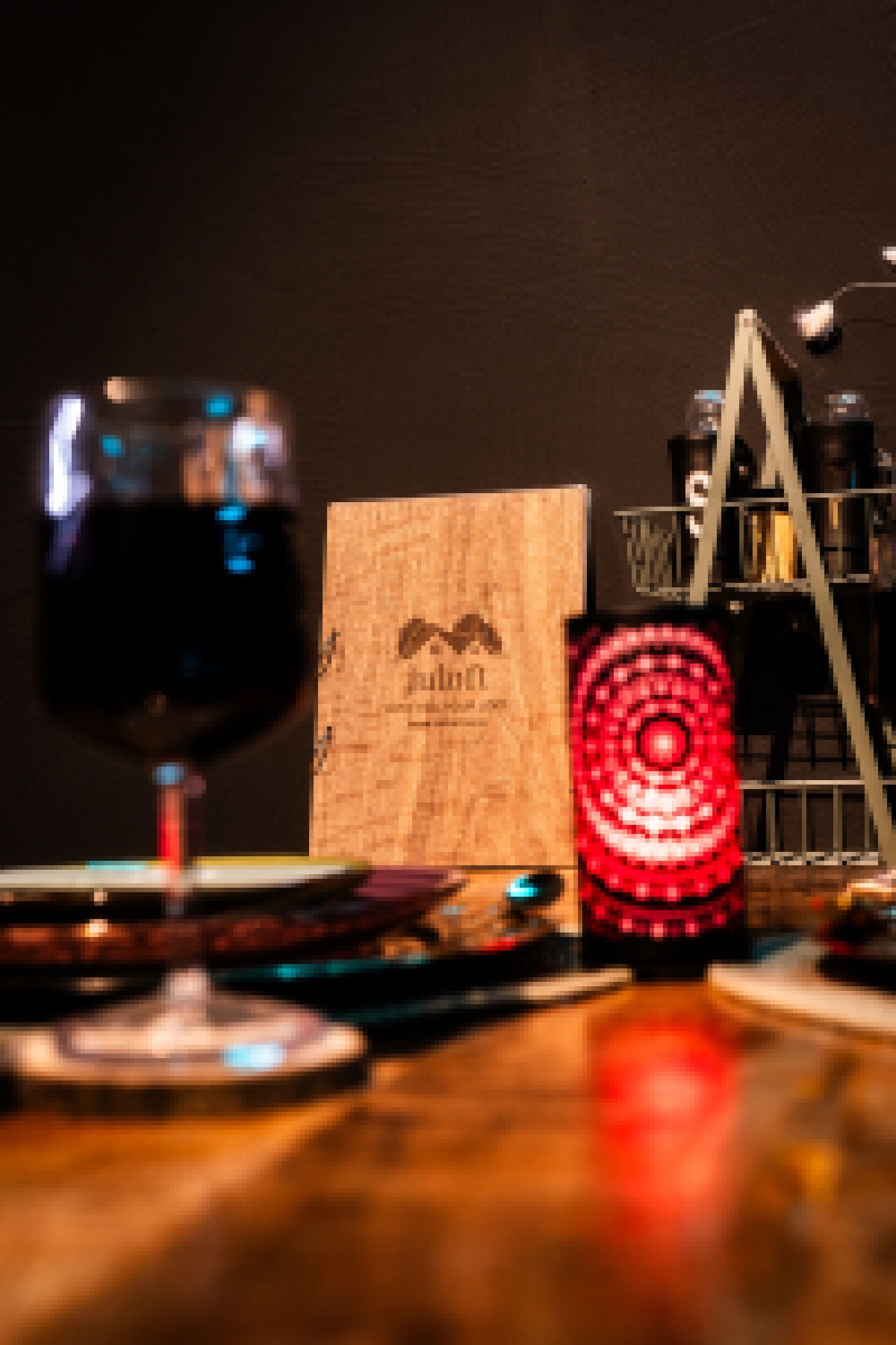 A wine glass, a wooden box, and a red circular object on a table.
