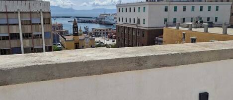 Une terrasse sur le toit offrant une vue sur le paysage urbain de la côte, avec ses bâtiments et une étendue d’eau.
