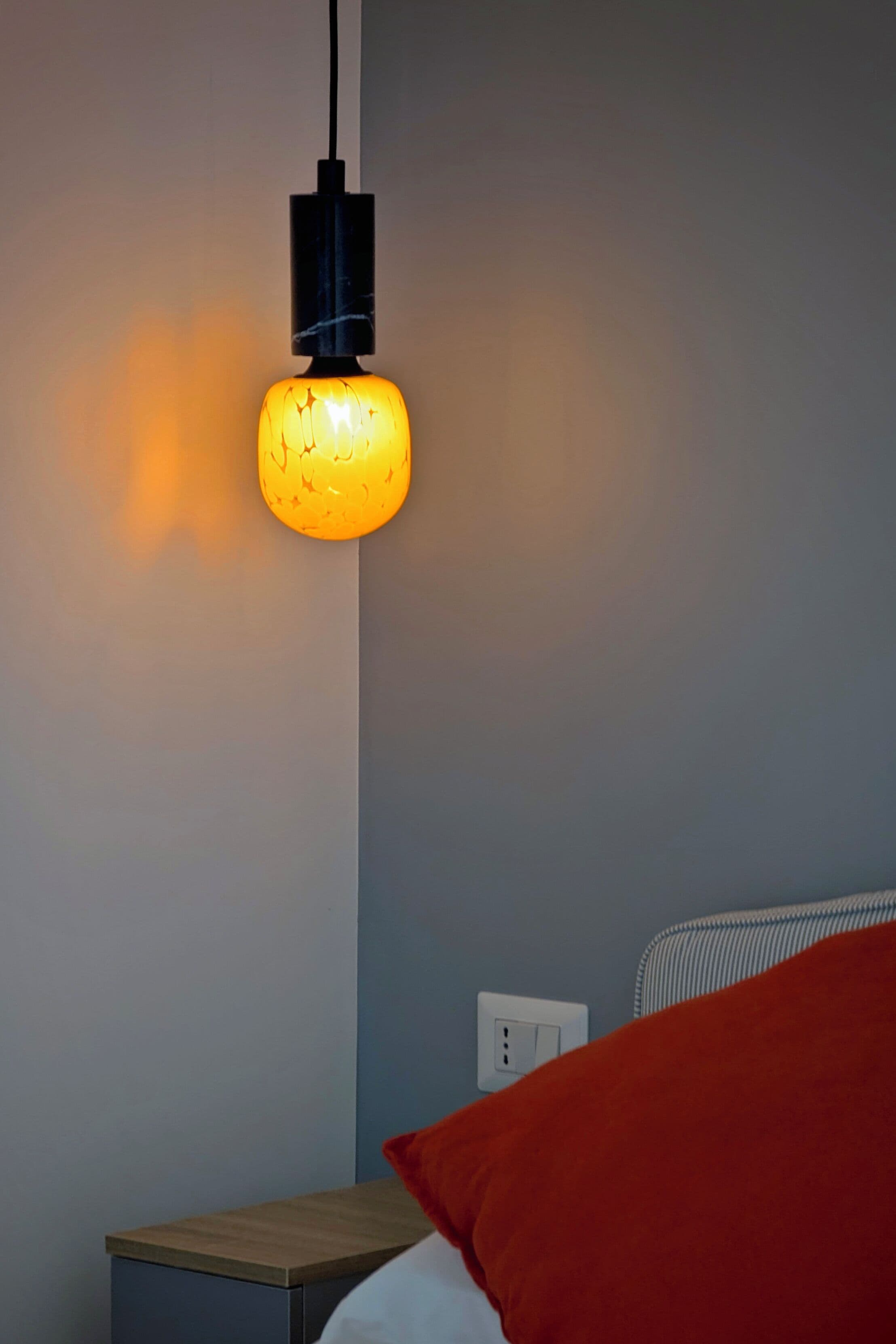 A room with a bed, a nightstand, and a wall socket.