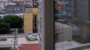 A view of a cityscape with buildings, a clock tower, and a body of water with mountains in the background. - Incoming Roof Bovio (Naples)