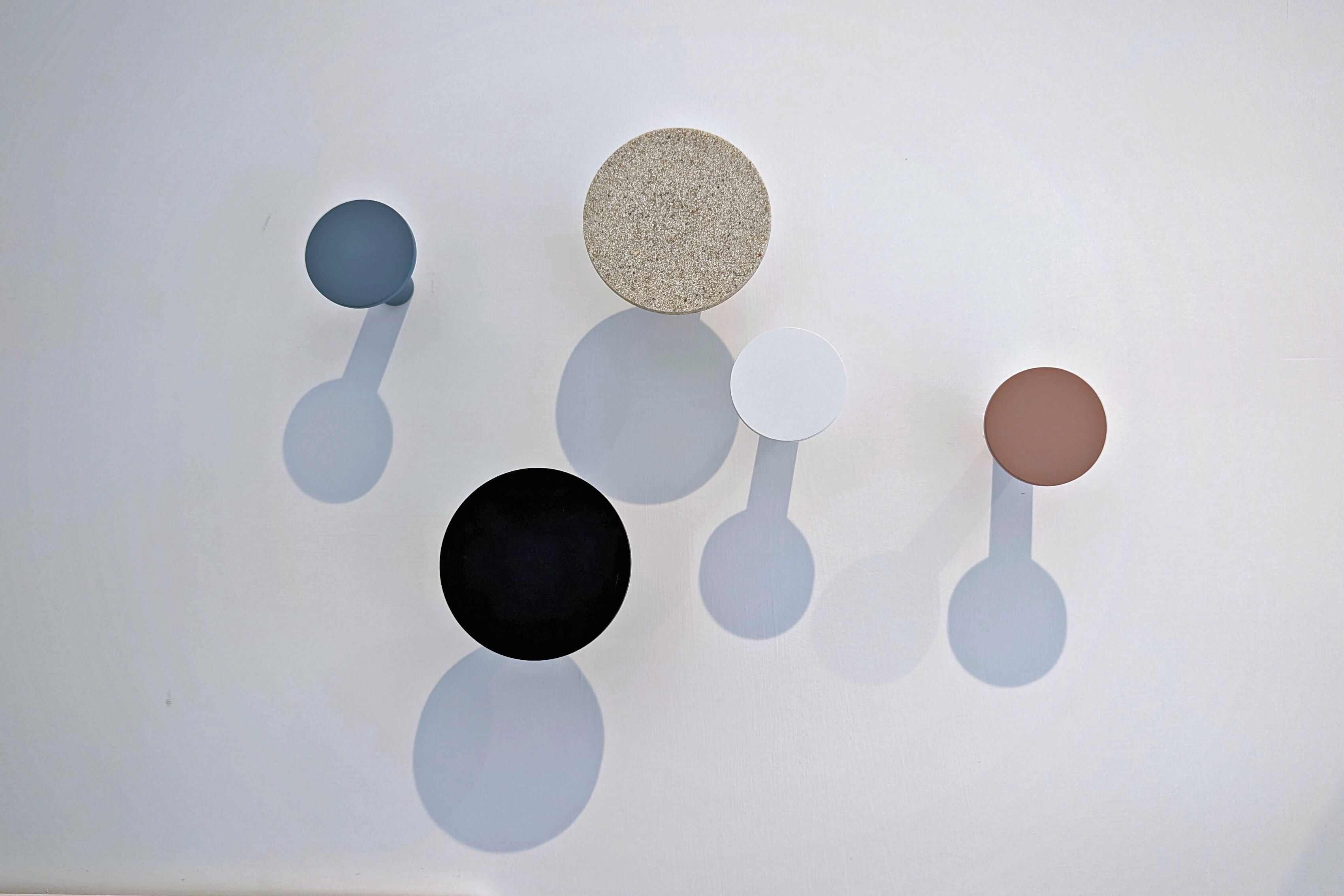 A white wall with five circular objects of varying sizes and textures.