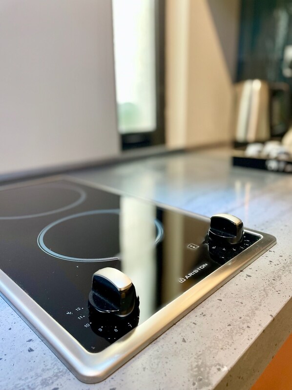 A modern kitchen with a black induction cooktop and stainless steel knobs.
