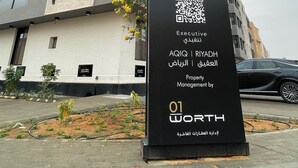 A modern building with a signboard displaying the name 'C Living' and a QR code. - C Living - Premium 3 Bedroom - AQIQ (Riyadh)