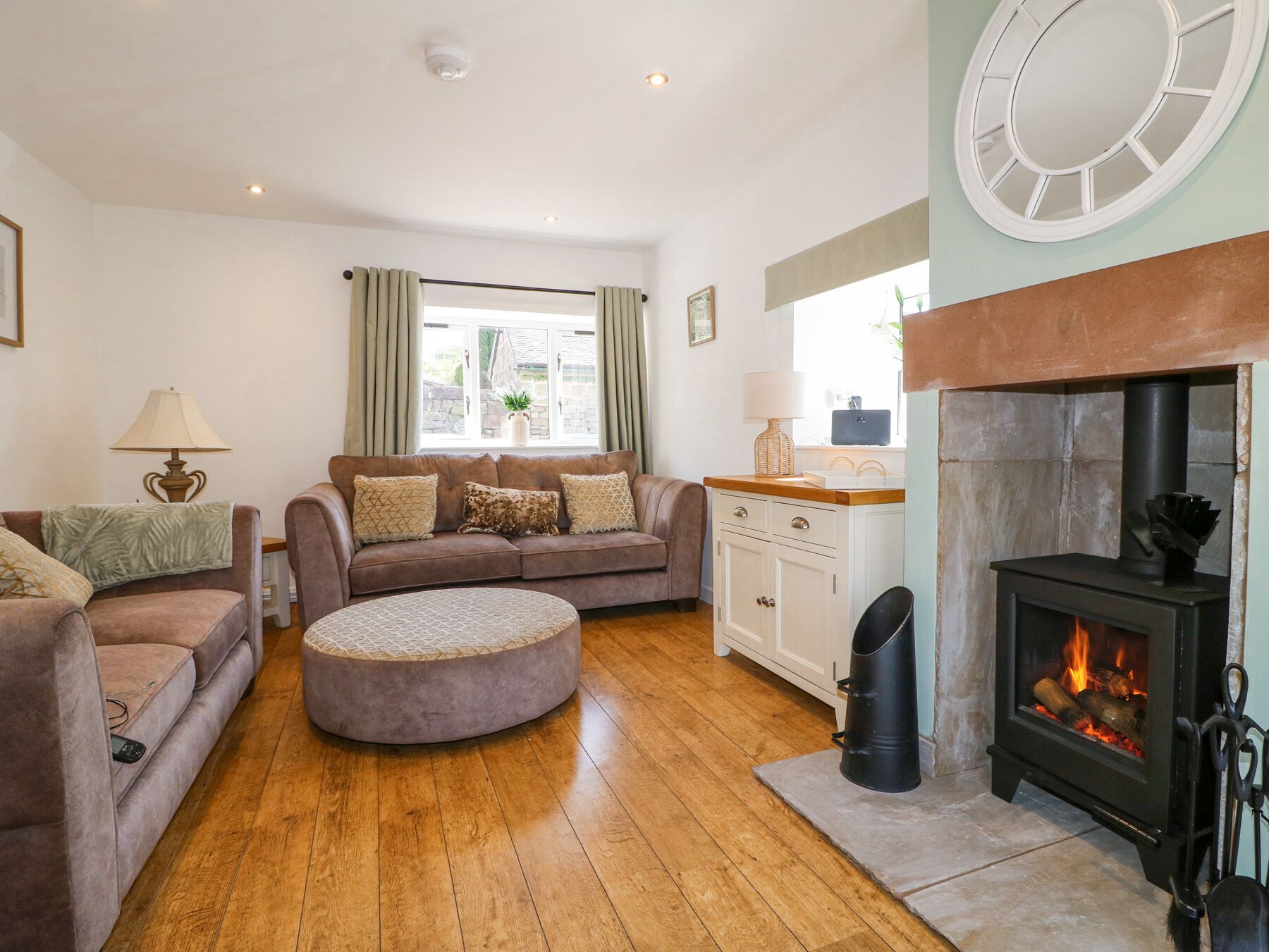 A cozy living room with a sofa, ottoman, and a fireplace.