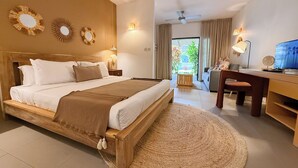 Ein Schlafzimmer mit Bett, Nachttischen, Schreibtisch, Stuhl, Fernseher und Blick ins Freie.