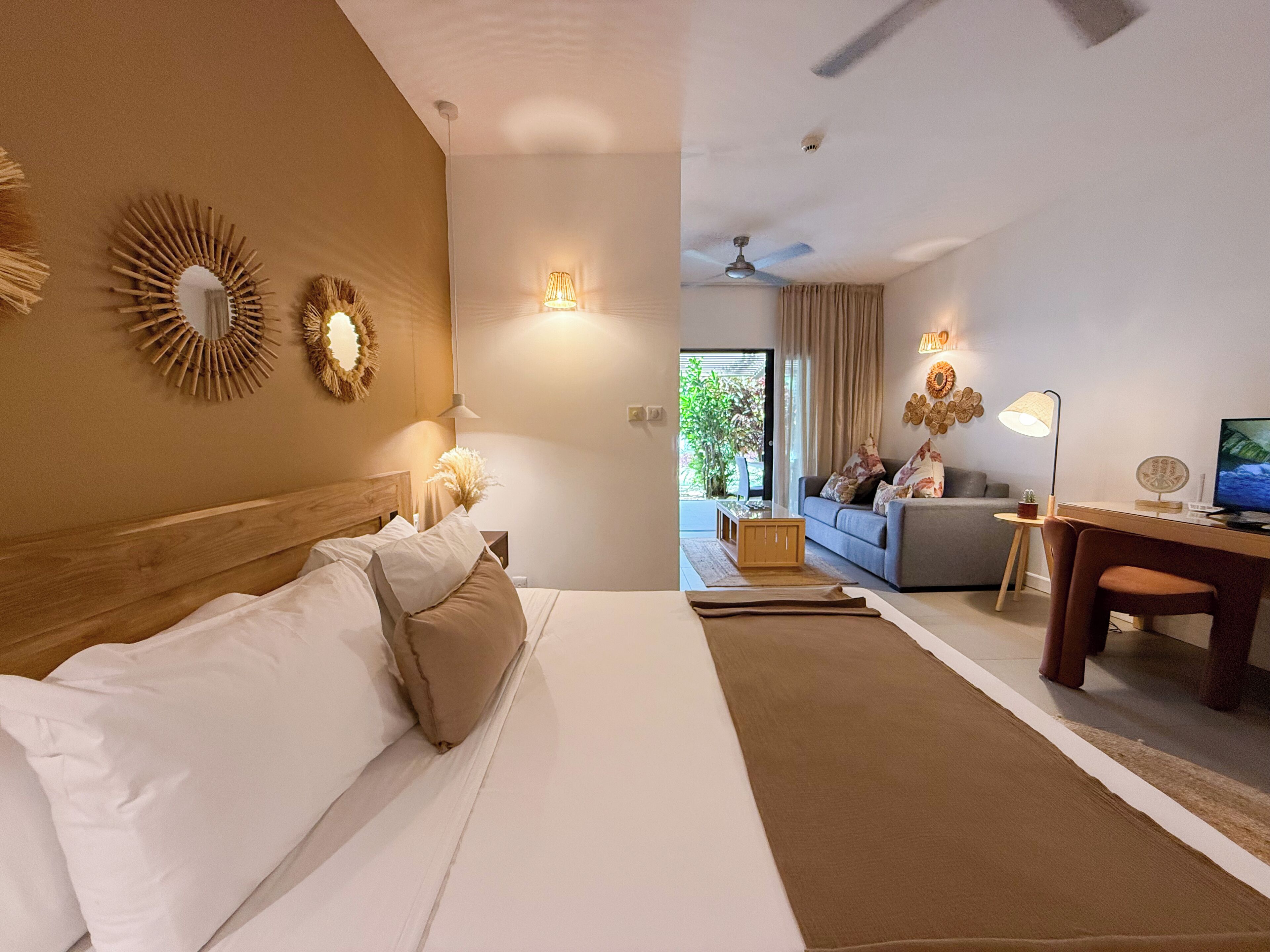 A hotel room with a bed, a desk, a sofa, and a TV.