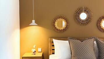 Un dormitorio con cama, mesita de noche y dos espejos en la pared.