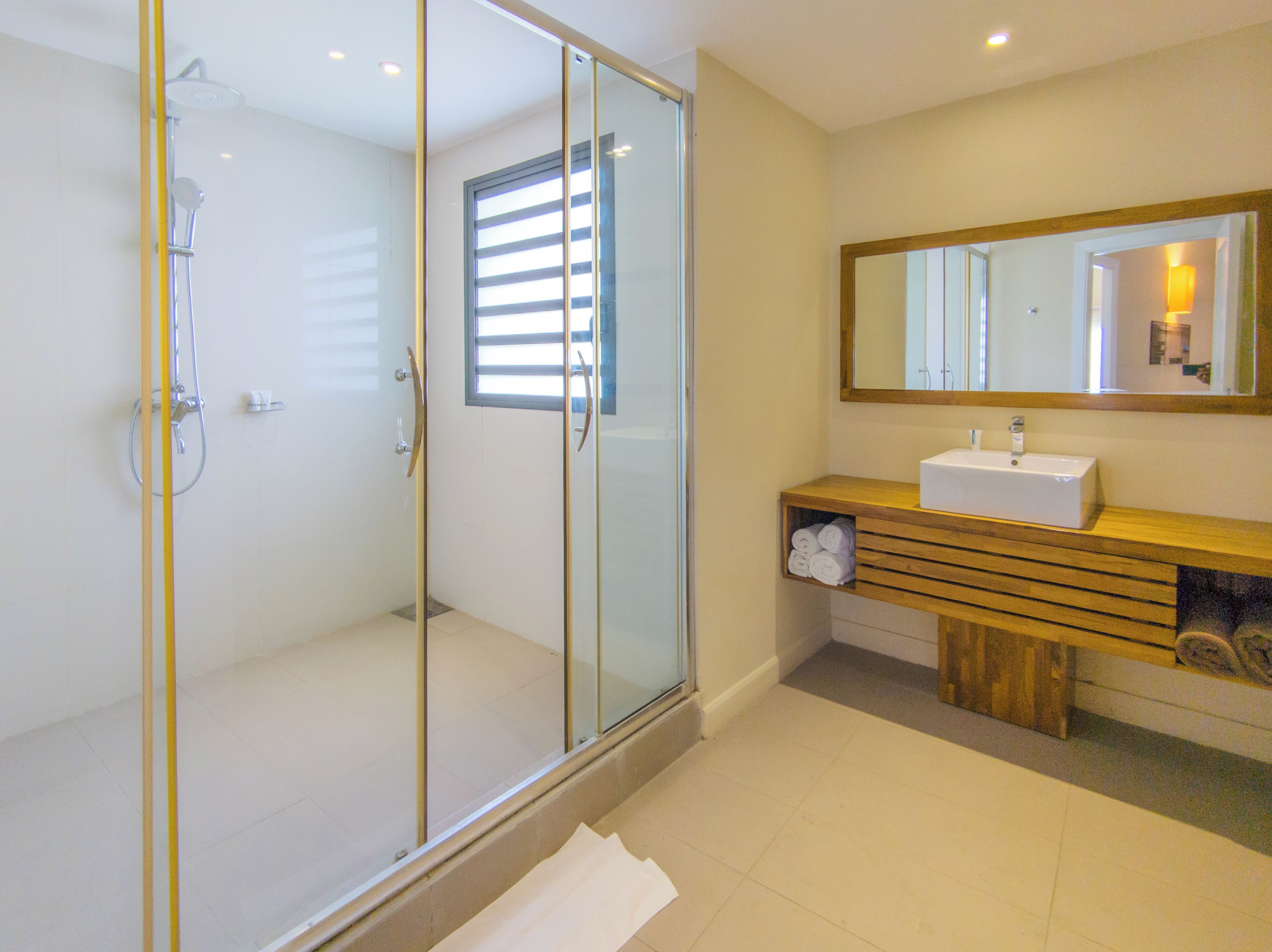 A modern bathroom with a glass-enclosed shower, a wooden vanity with a sink, and a large mirror above the vanity.