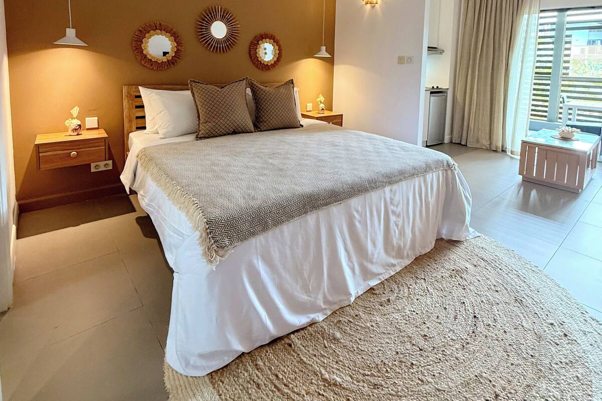 Un dormitorio con una cama grande, ventilador de techo, apliques de pared y vista al exterior.