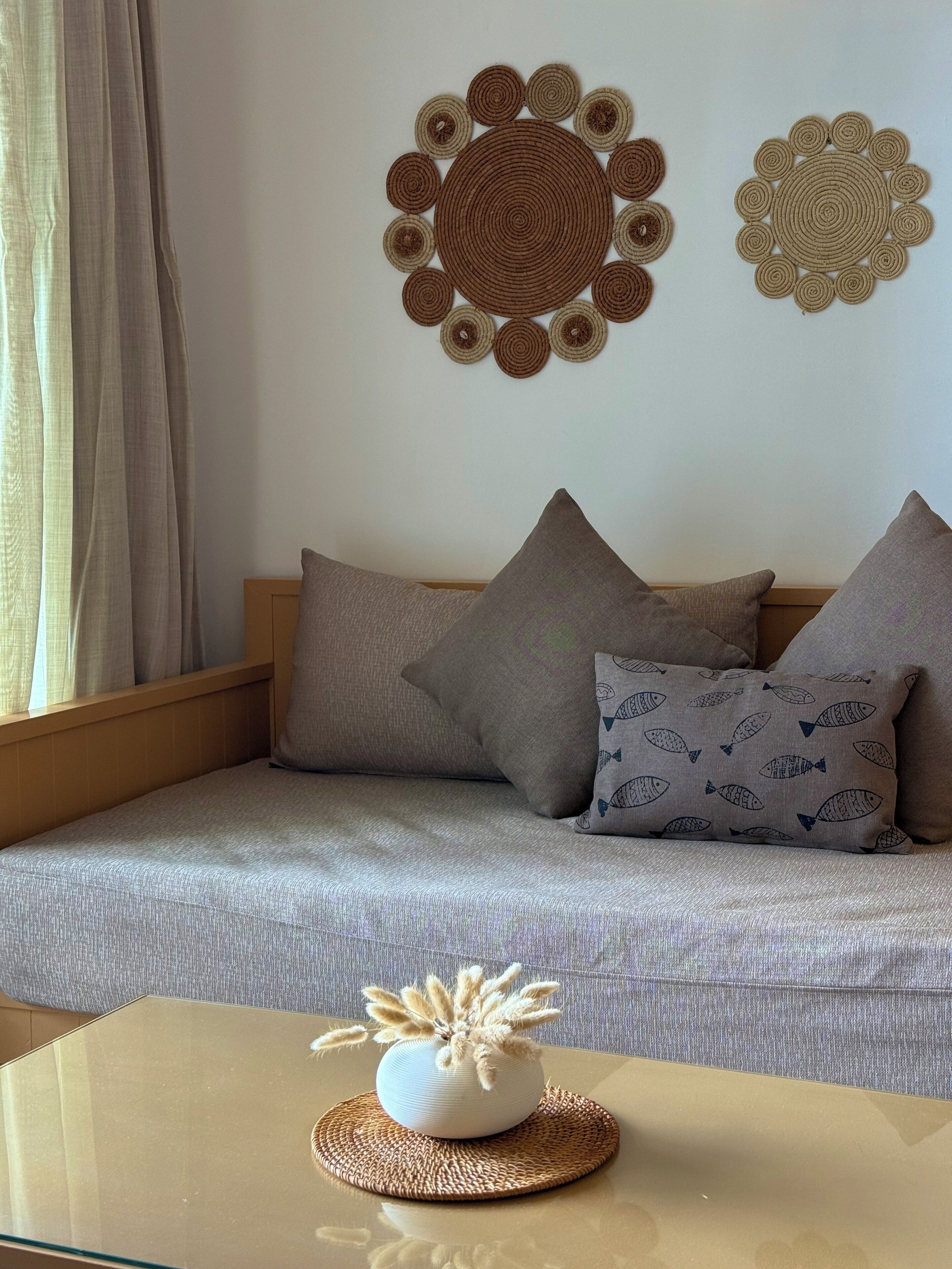 A living room with a sofa, decorative wall hangings, and a small table with a vase.