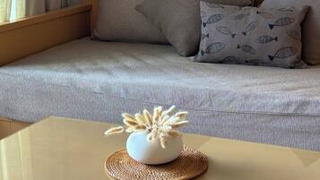 A living room with a sofa, decorative wall hangings, and a small table with a vase.