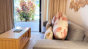 Ein Wohnzimmer mit einer Couch, einem Couchtisch und Blick auf einen Garten durch eine Glastür.