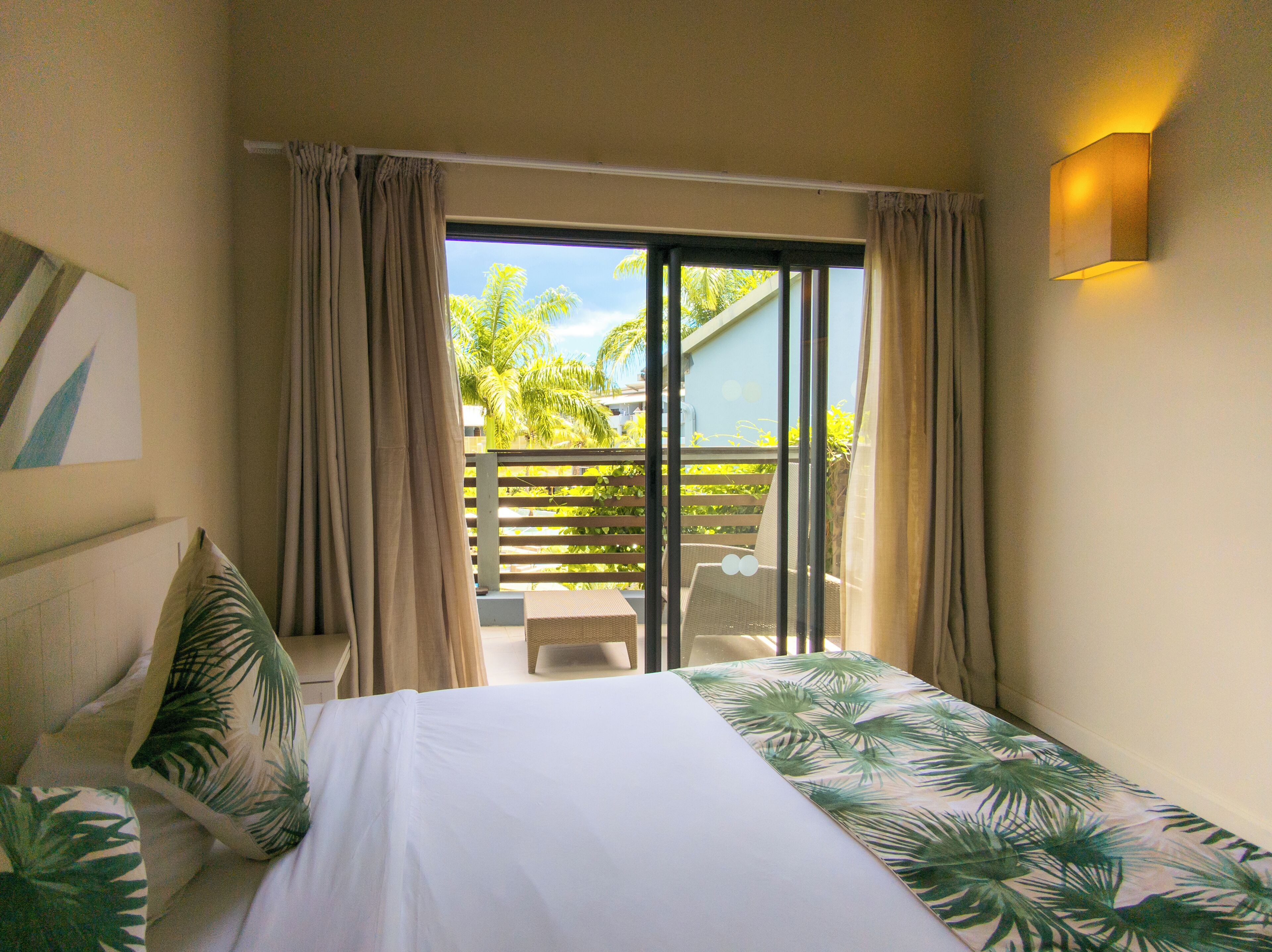 Ein Hotelzimmer mit Bett, Blick ins Freie und einem Balkon mit einem Stuhl.
