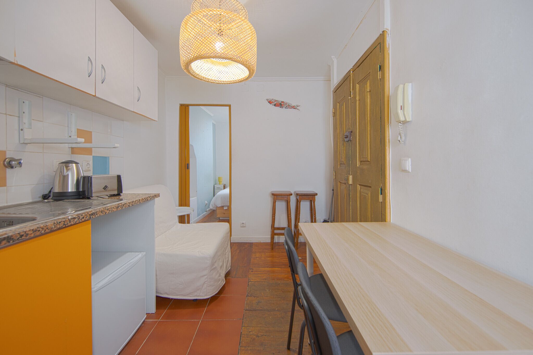 A compact kitchen with a dining area, a bed, and a bathroom visible through an open door.