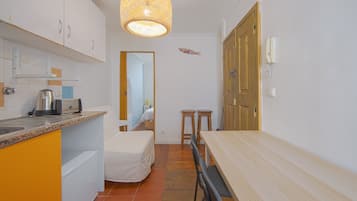 A compact kitchen with a dining area, a bed, and a bathroom visible through an open door.