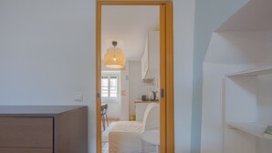 A narrow hallway leading to a bedroom with a bed, a chair, and a kitchenette area. - Alfama Cosy by Homing (Lisbon)