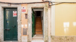 A narrow stairway leading to a door with a green frame, a sign indicating a fire alarm, and a number '37' above the door. - Alfama Cosy by Homing (Lisbon)