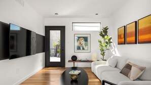 A modern living room with a black coffee table, a grey sofa, and a TV mounted on the wall.