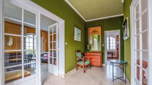 A room with a green wall, a wooden dresser, a green chair, and a glass table. - Spacious family home in Brizay, Near Chinon and Azay-le-Rideau (Up to 15 Guests) (Brizay)