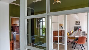A modern kitchen with a dishwasher, wooden cabinets, and a view through a glass door to a dining area with a long table and colorful chairs. - Spacious family home in Brizay, Near Chinon and Azay-le-Rideau (Up to 15 Guests) (Brizay)
